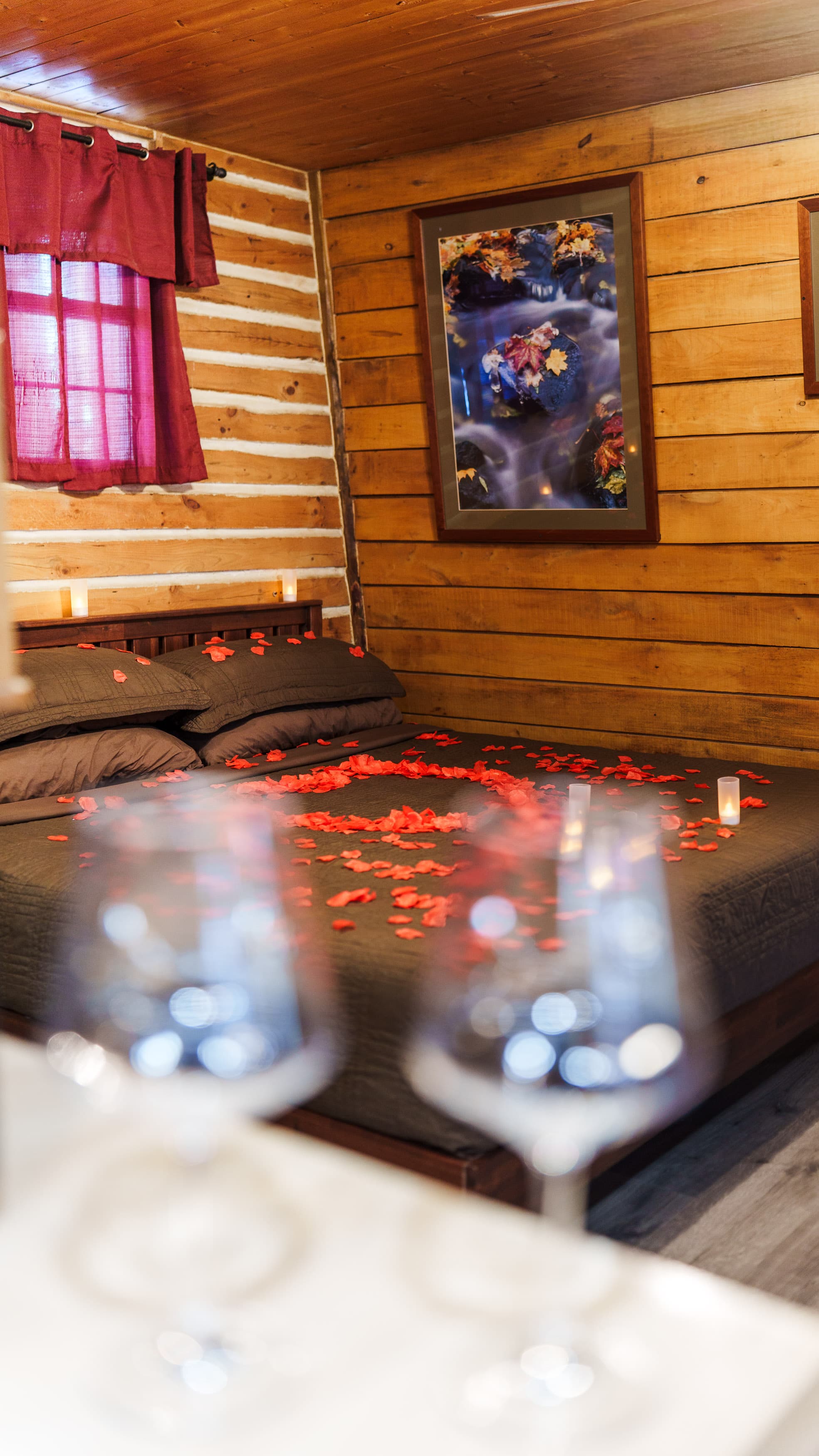 A romantic bedroom featuring a bed adorned with rose petals and soft lighting.