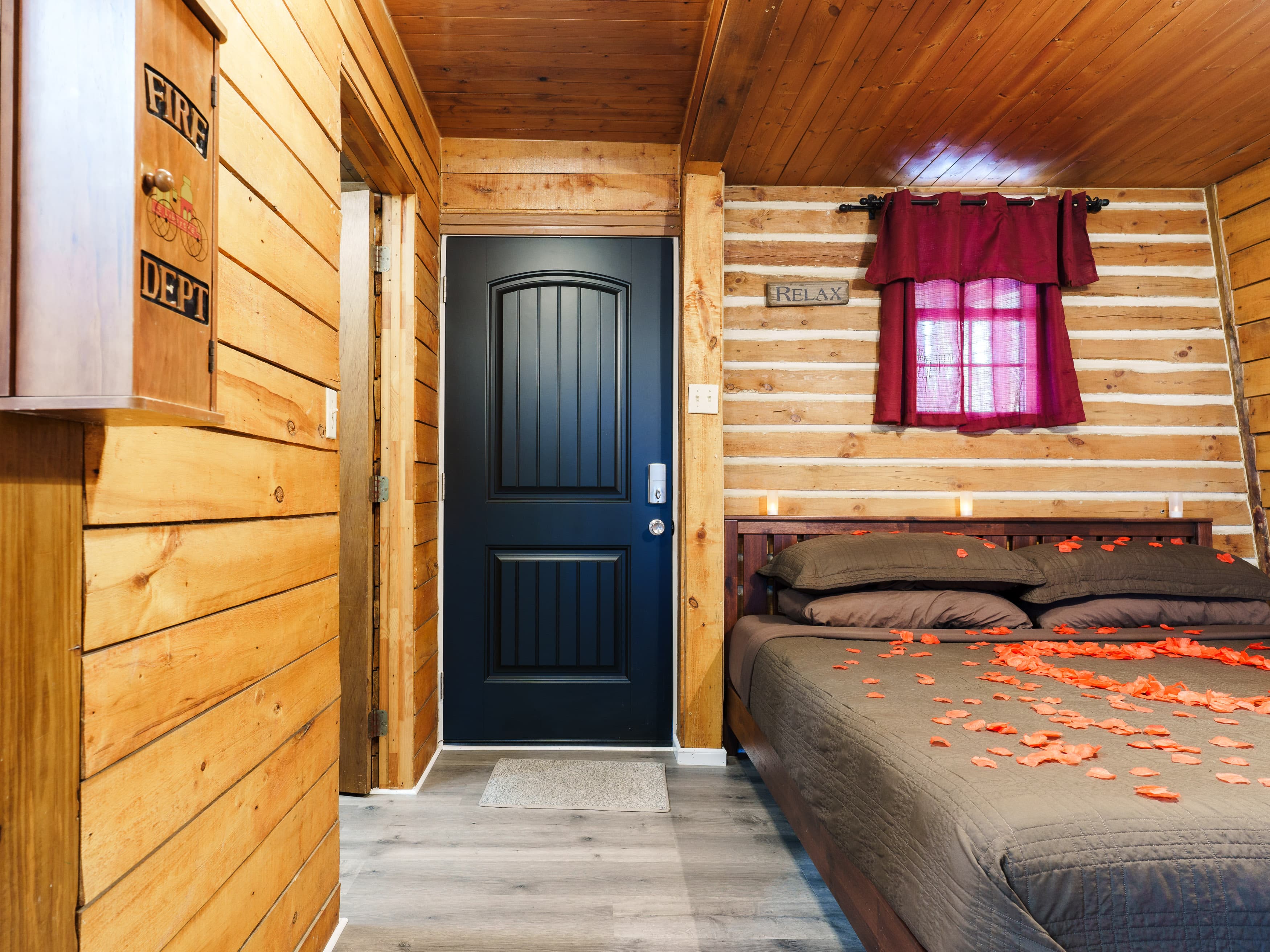 Cozy cabin interior featuring a bed adorned with rose petals and a door leading outside.