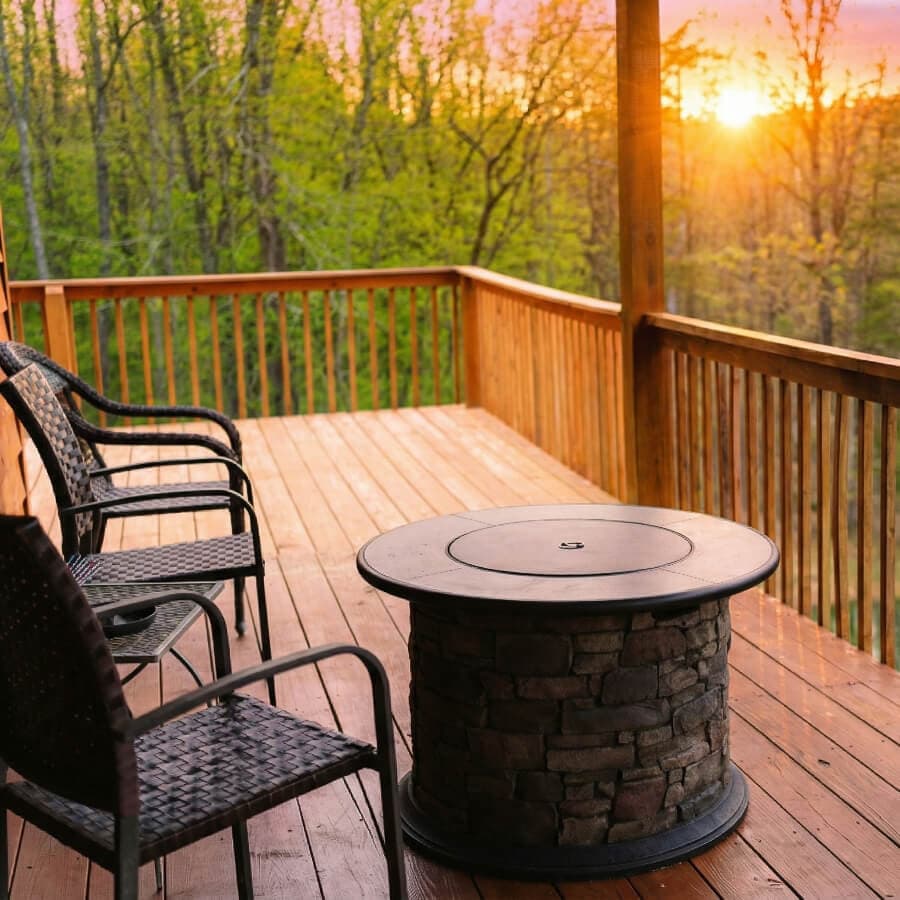A wooden deck at sunset features a circular stone table and four chairs.