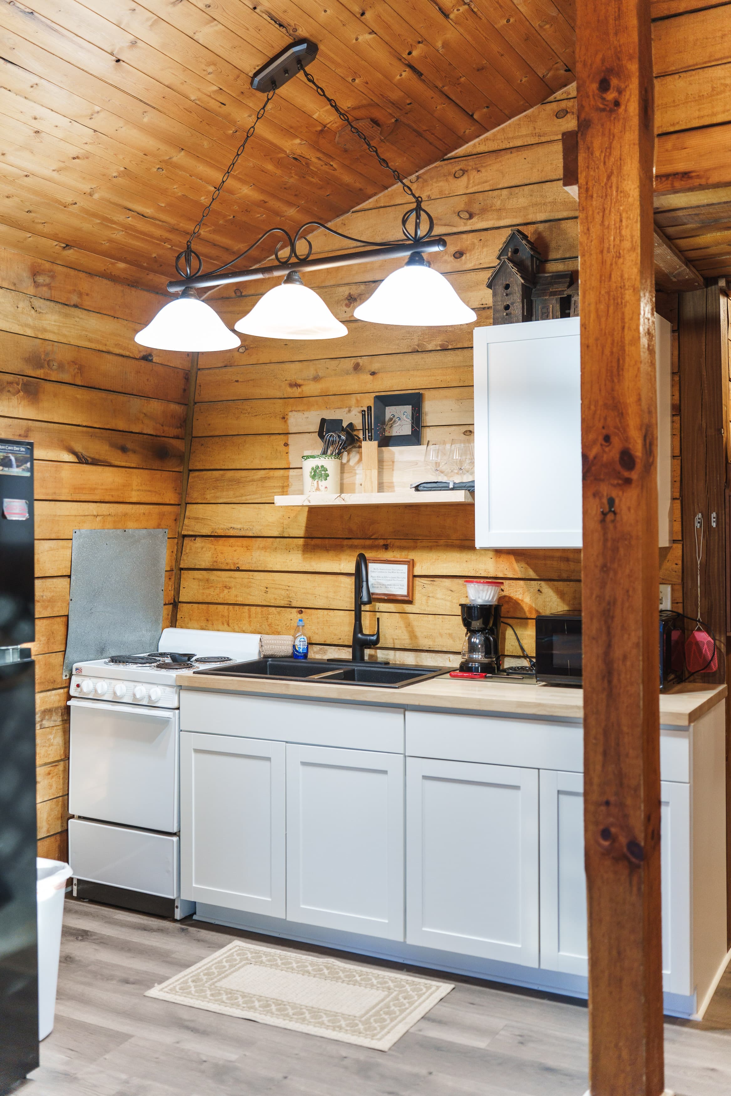 A cozy kitchen featuring wooden walls, a gas stove, a double sink, and modern appliances.