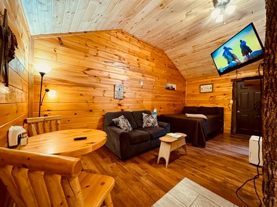 Cozy wooden cabin interior featuring a living area, dining table, and television.