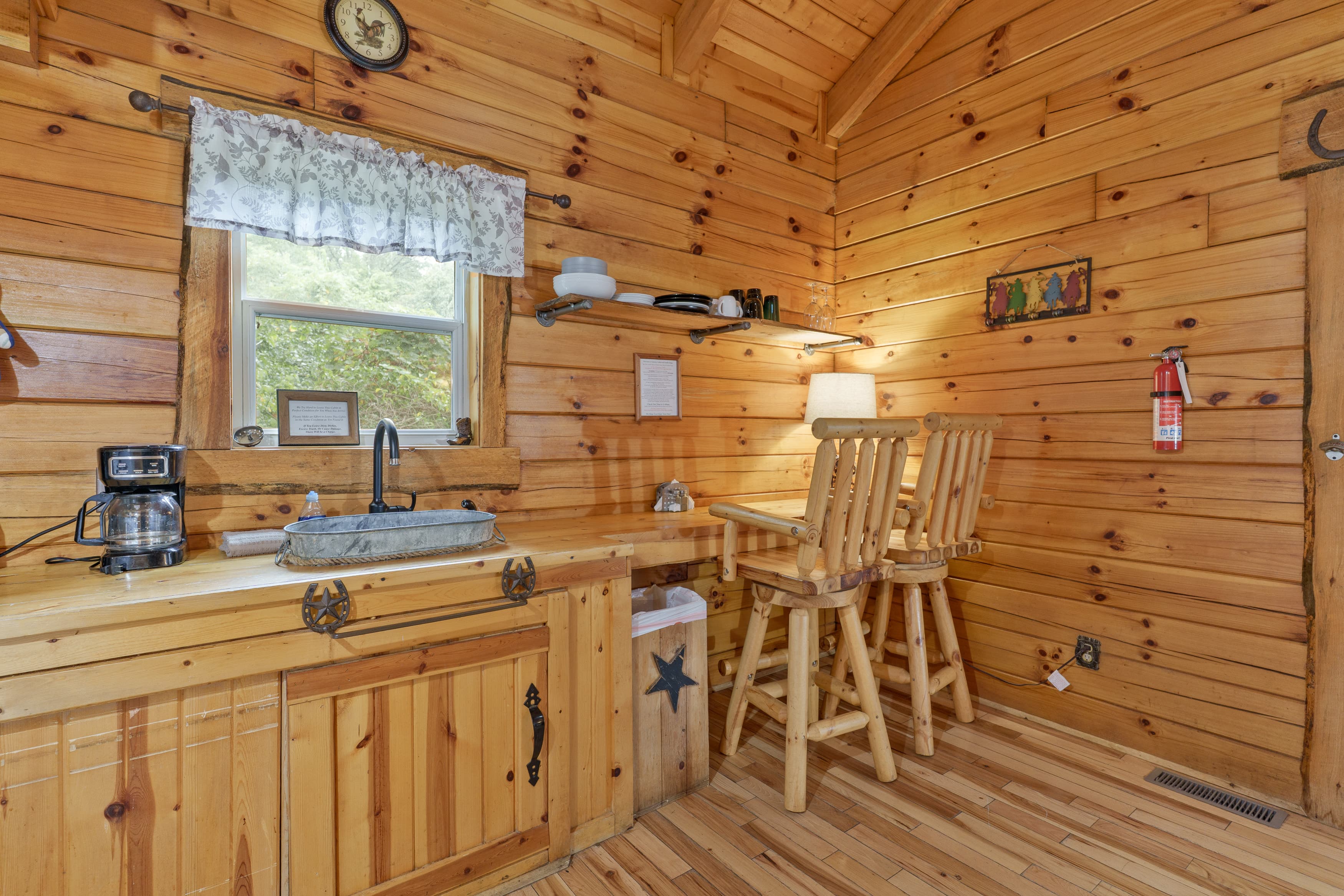 A cozy wooden kitchen with a small countertop, two stools, and rustic decor.
