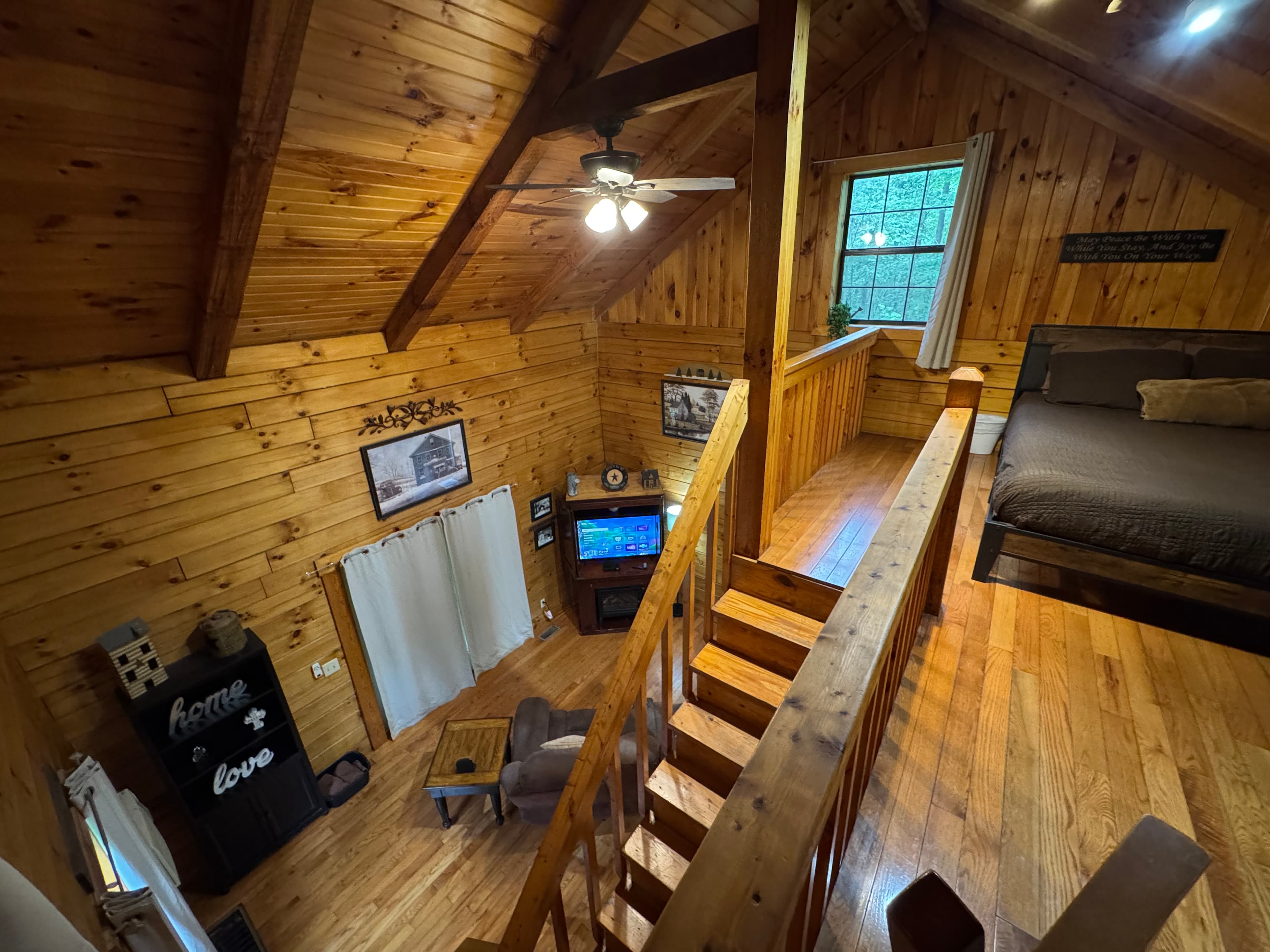Cozy wooden loft interior featuring a bed, seating area, and staircase.