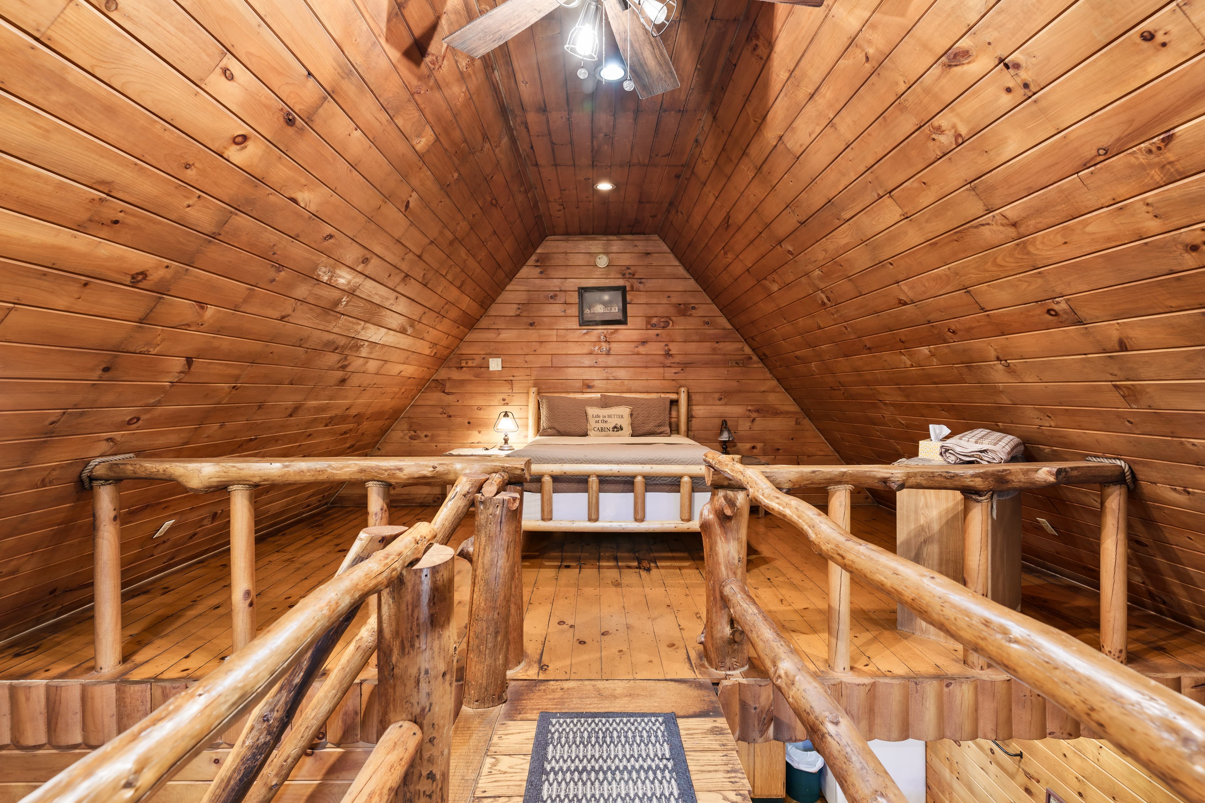Cozy wooden attic loft with a bed and rustic railing.