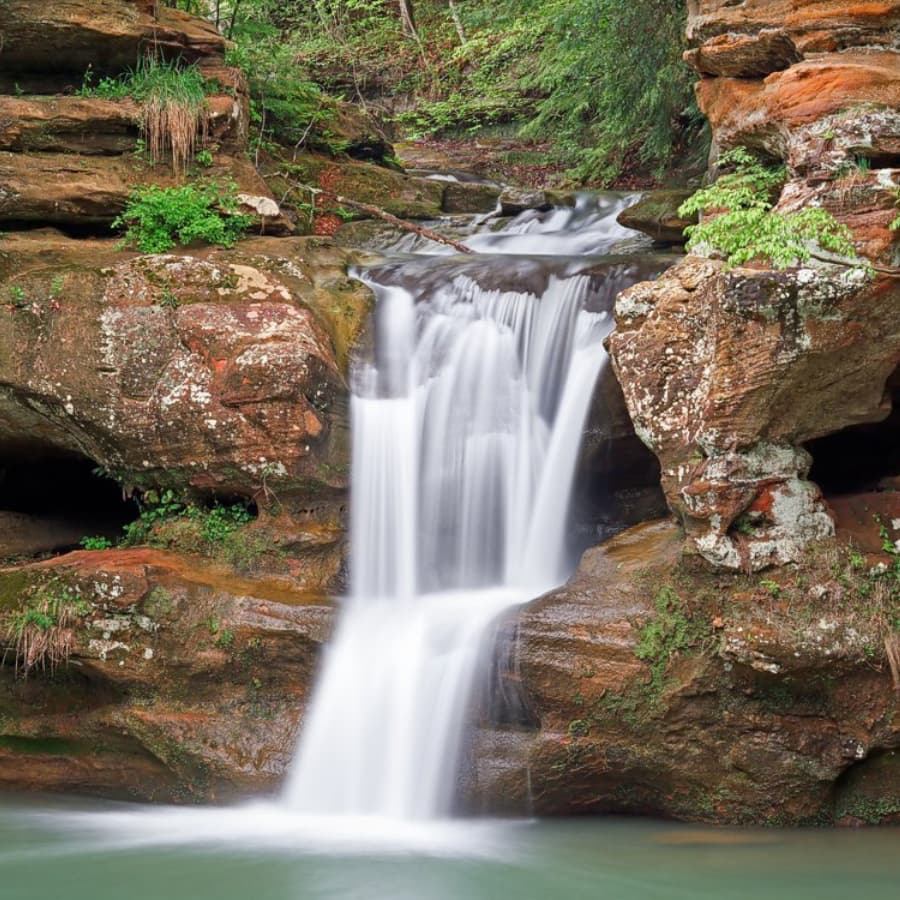 A serene waterfall cascading over rocky ledges surrounded by lush greenery.