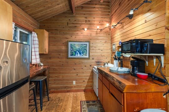 A cozy wooden kitchen featuring a stainless steel refrigerator, wooden countertops, and natural light.