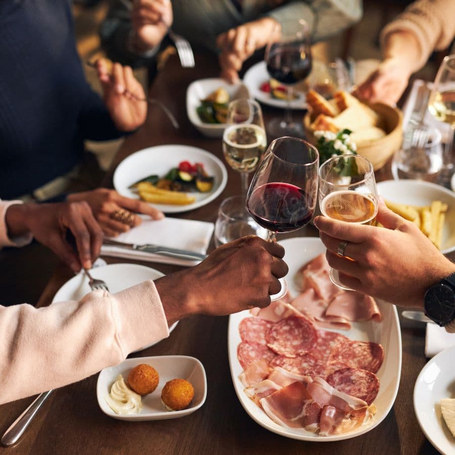 A group of people enjoying a meal and toasting with glasses of wine and beer.