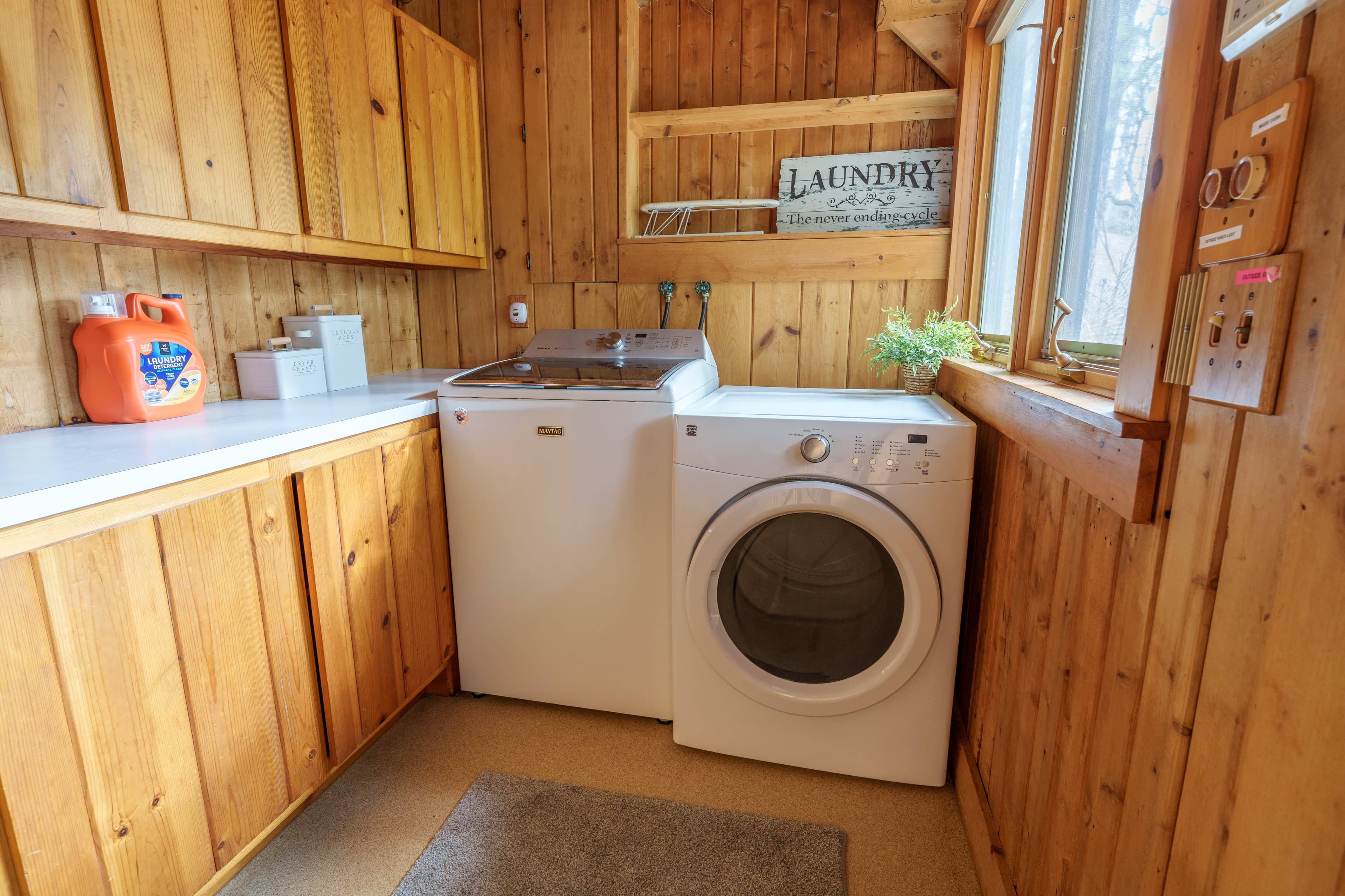 A laundry room with a washer and dryer against wooden walls and a window.