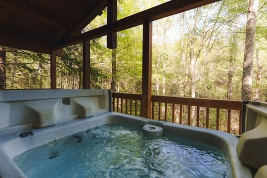 Hot tub on a balcony overlooking a serene forest.