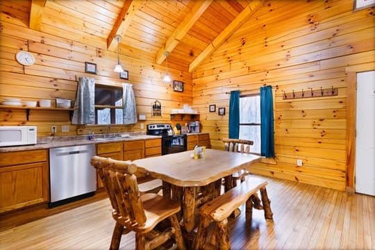 A cozy wooden kitchen featuring a dining table, rustic furniture, and modern appliances.