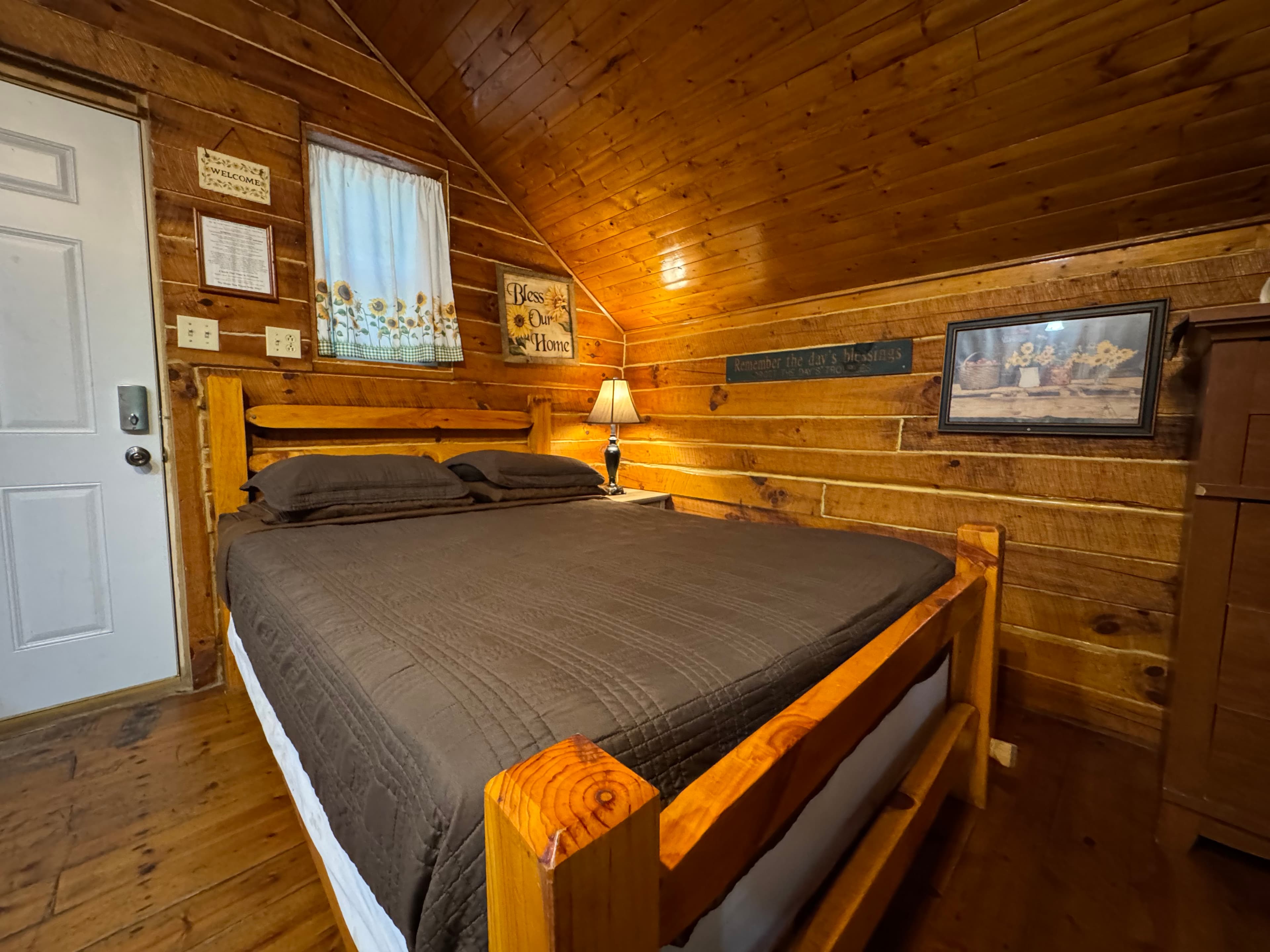 Cozy wooden bedroom with a double bed, lamp, and decorative wall accents.