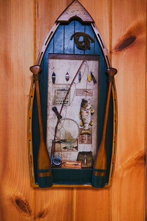 Framed fishing-themed decor featuring a fish and fishing equipment on a wooden background.