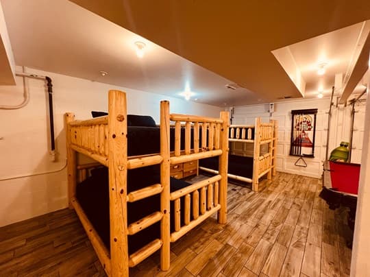A cozy room featuring two wooden bunk beds with dark bedding.