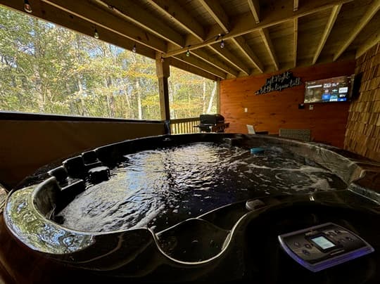 A tranquil hot tub sits on a covered porch, surrounded by trees and outdoor furniture.