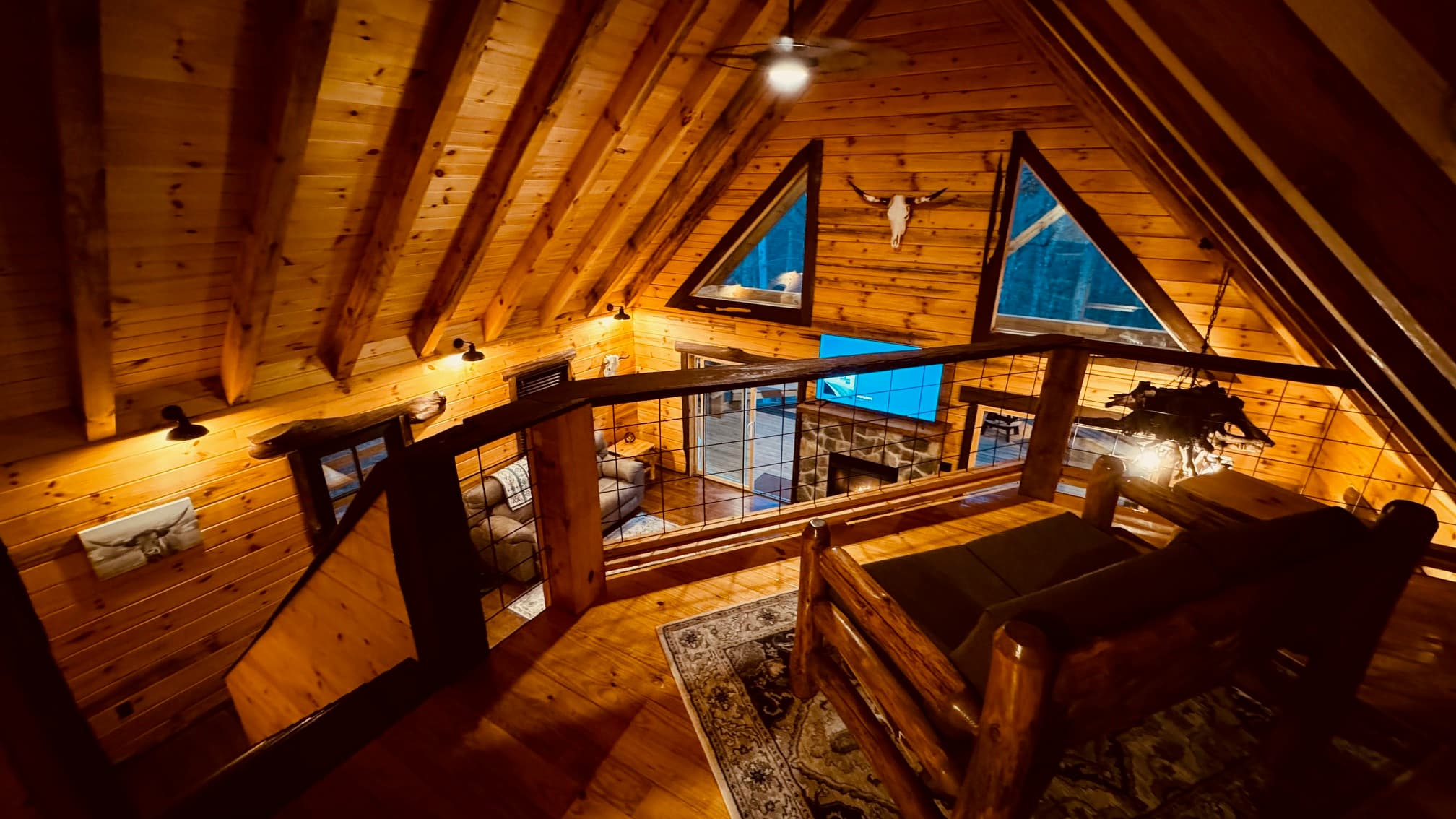 A cozy wooden loft with triangular windows and rustic decor.