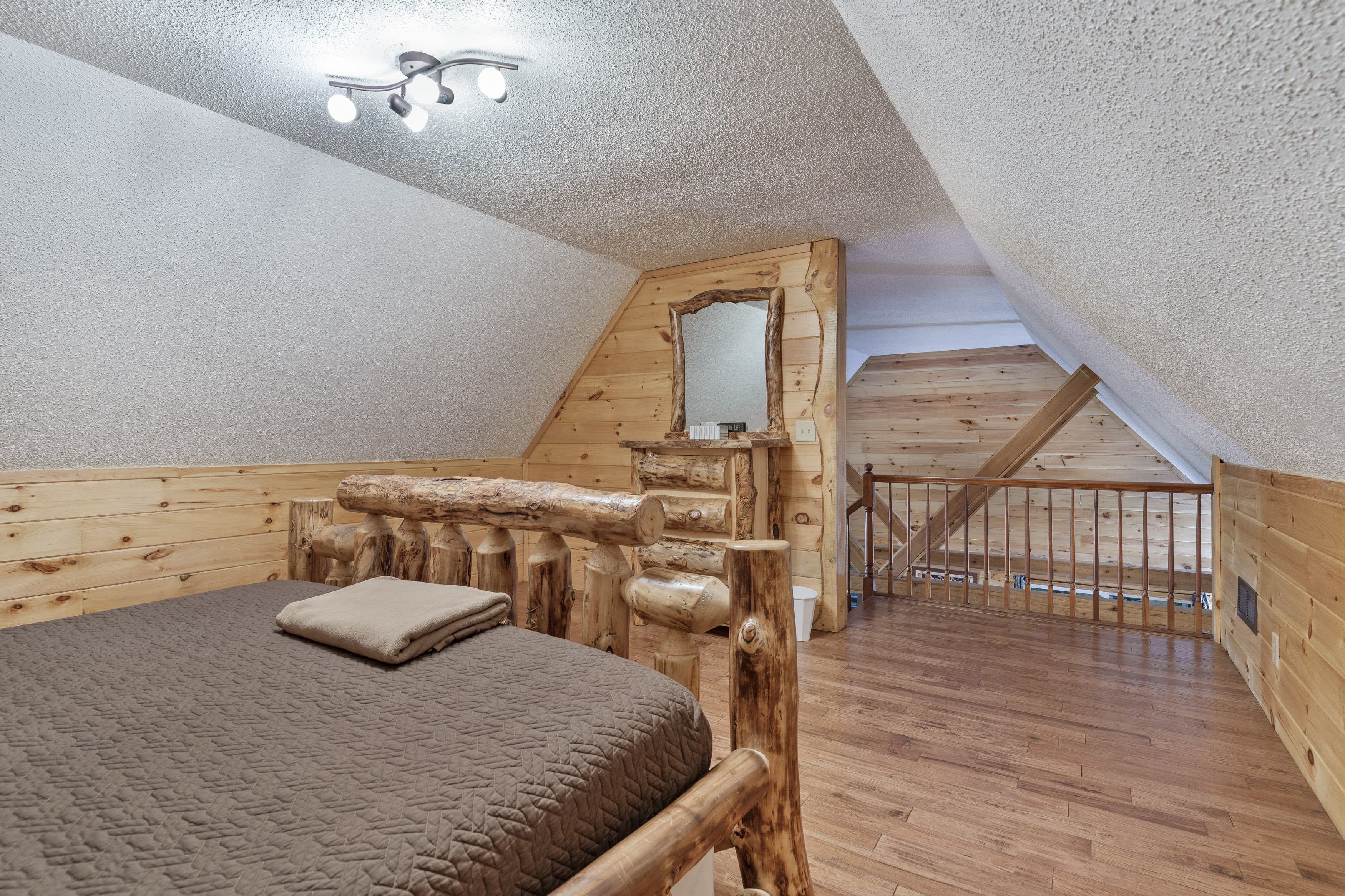 Cozy wooden attic bedroom featuring a log bed and mirror.