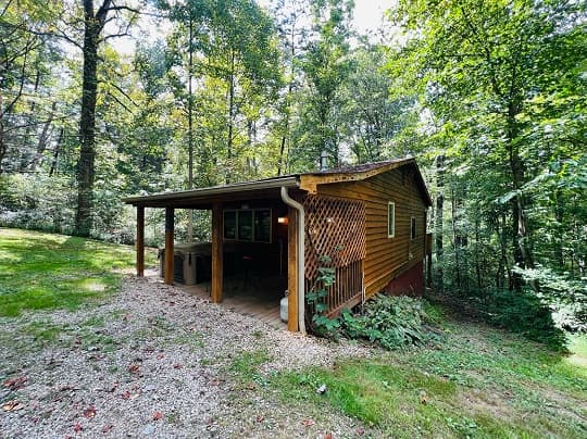 A small wooden cabin nestled in a green, wooded area.
