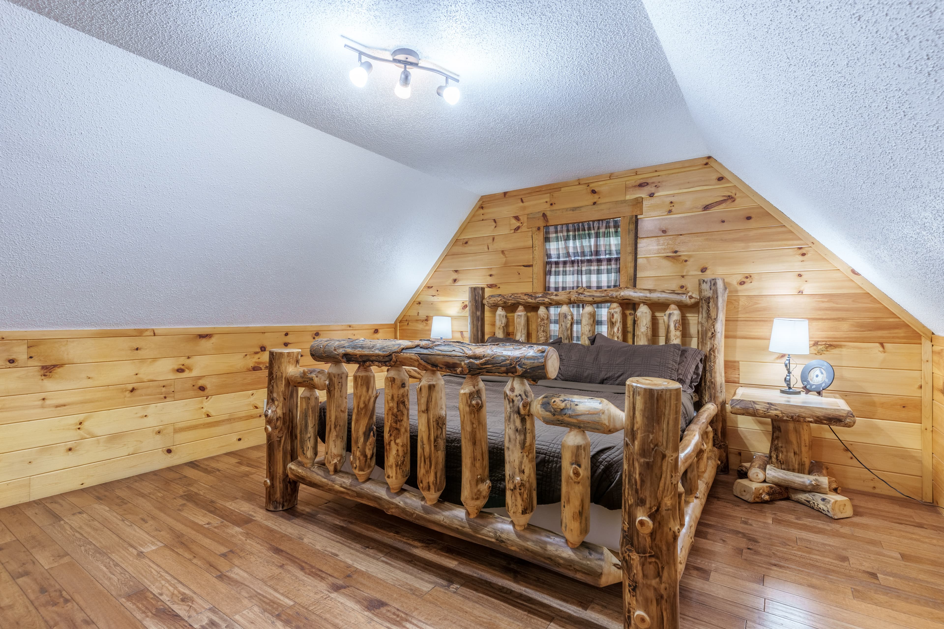 Cozy wooden bedroom with a rustic log bed and warm, natural wood paneling.
