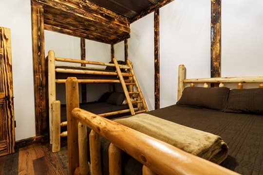A cozy bedroom featuring a wooden bunk bed and a separate queen-sized bed.