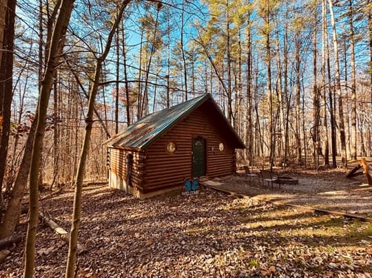 A cozy log cabin surrounded by trees in a wooded area.