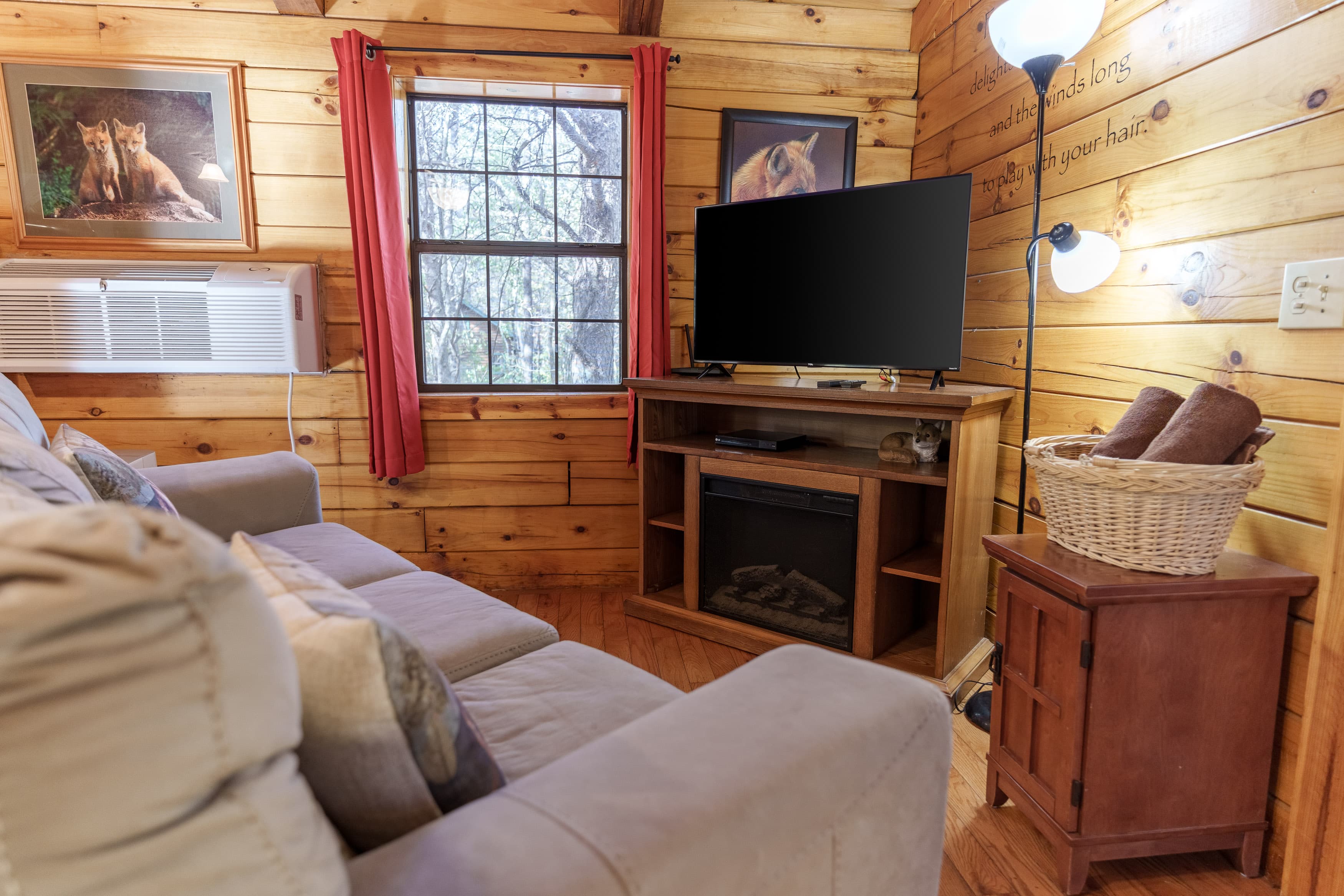Cozy sitting area featuring a sofa, television, and wooden accents with nature-themed wall art.
