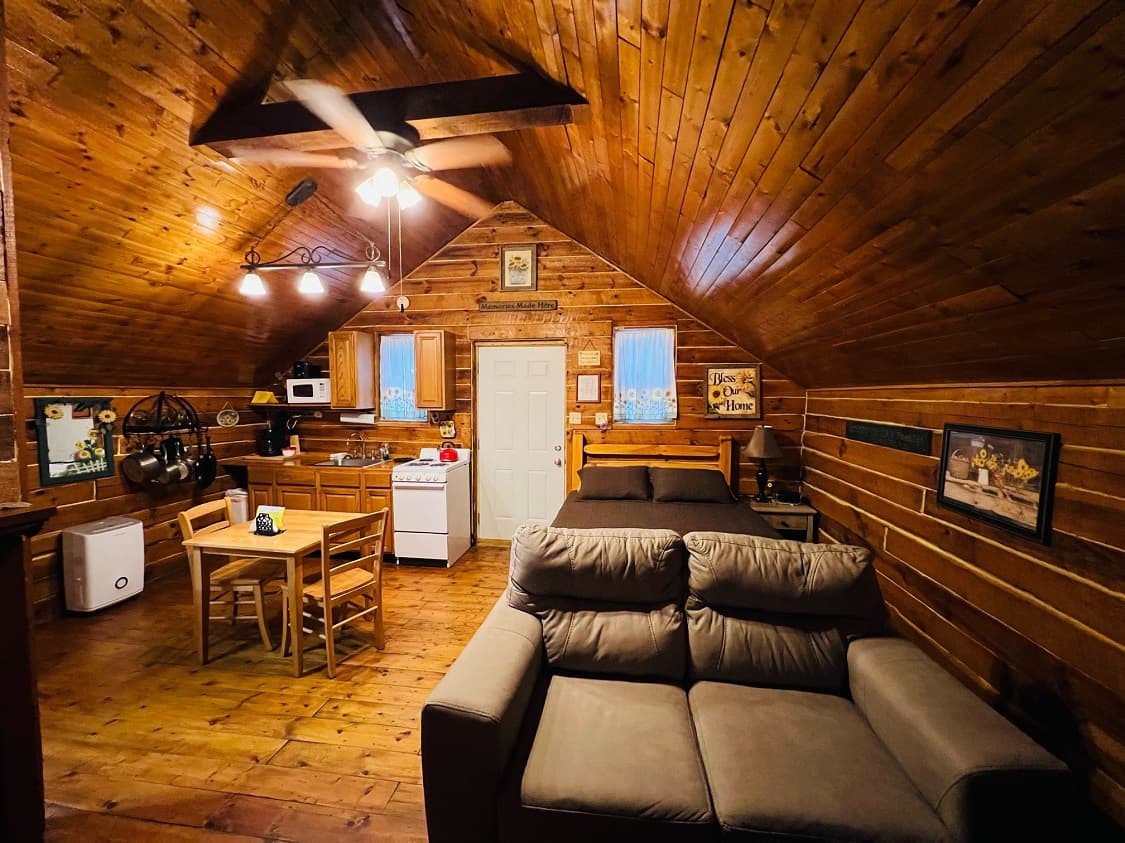 A cozy wooden cabin interior featuring a kitchen, dining table, and living area.
