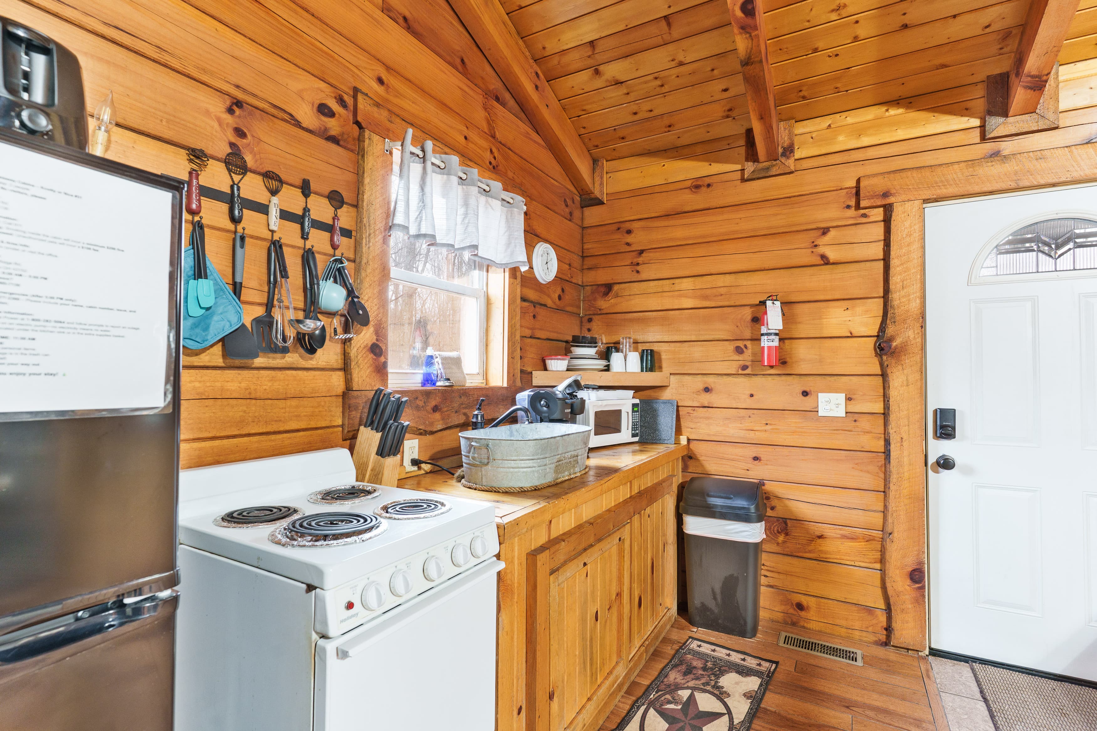 Cozy wooden kitchen featuring a stove, microwave, and rustic decor.