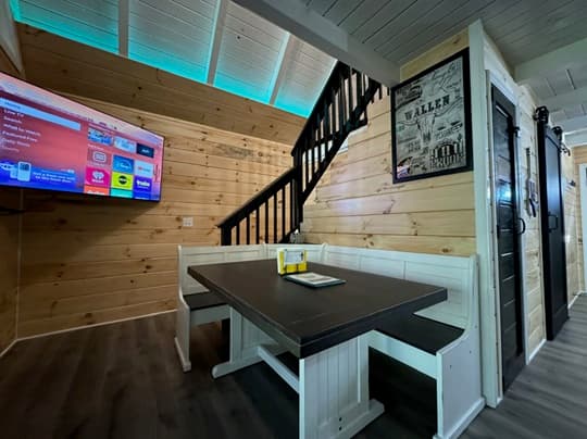 Cozy interior featuring a dining table, TV, and wooden walls with blue lighting.
