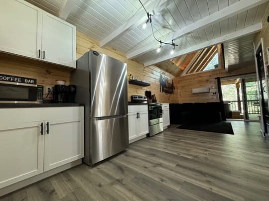 A modern kitchen with white cabinets, stainless steel appliances, and wooden accents.