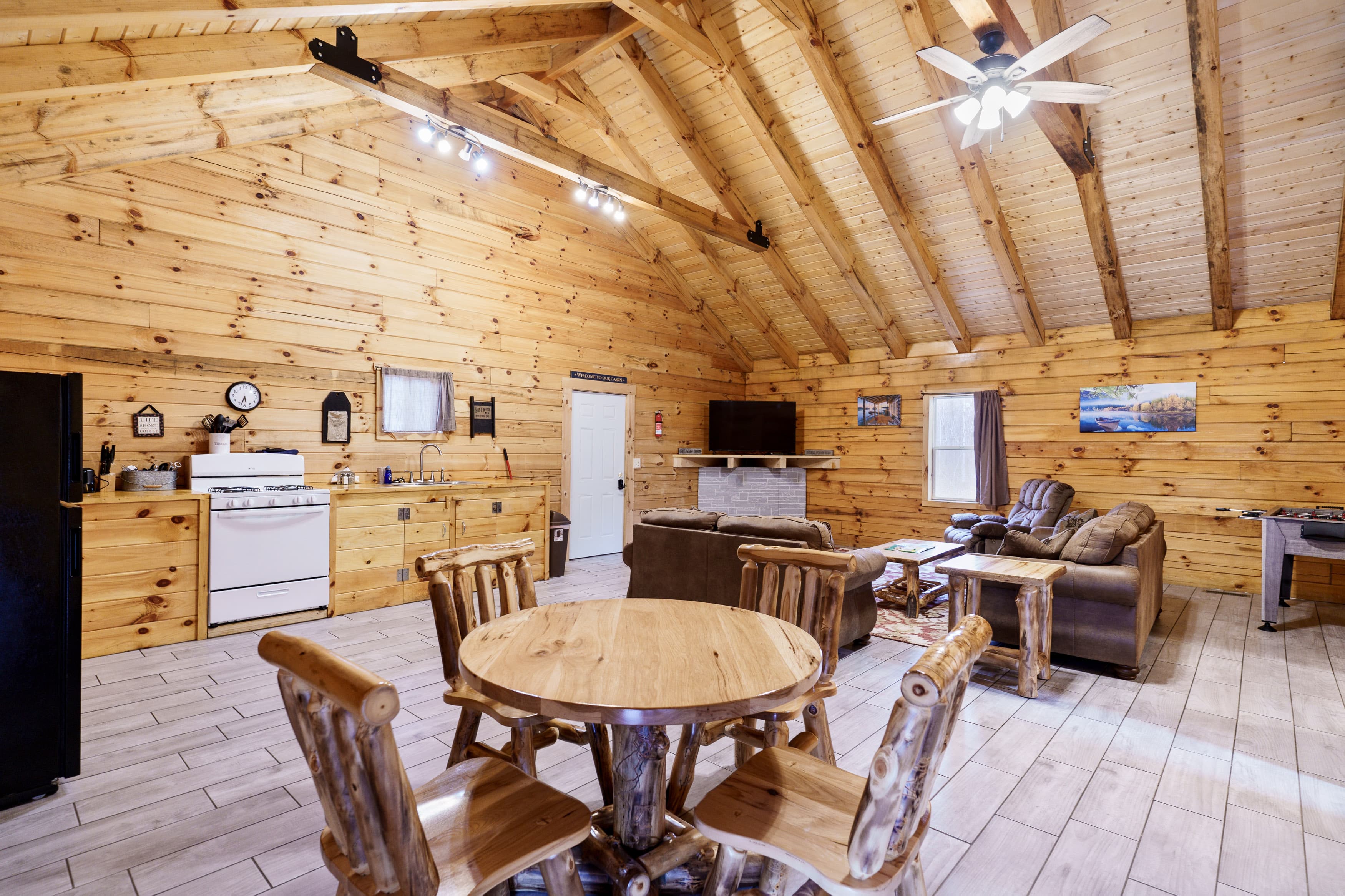 Cozy wooden interior of a cabin featuring a dining table, kitchen appliances, and a living area.