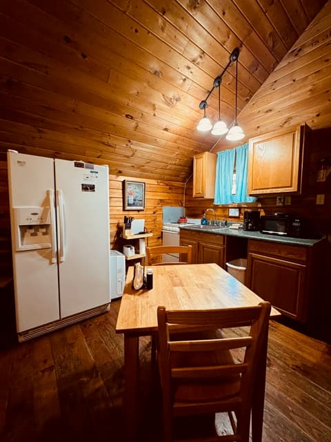 Cozy wooden kitchen with a dining table, refrigerator, and various appliances.