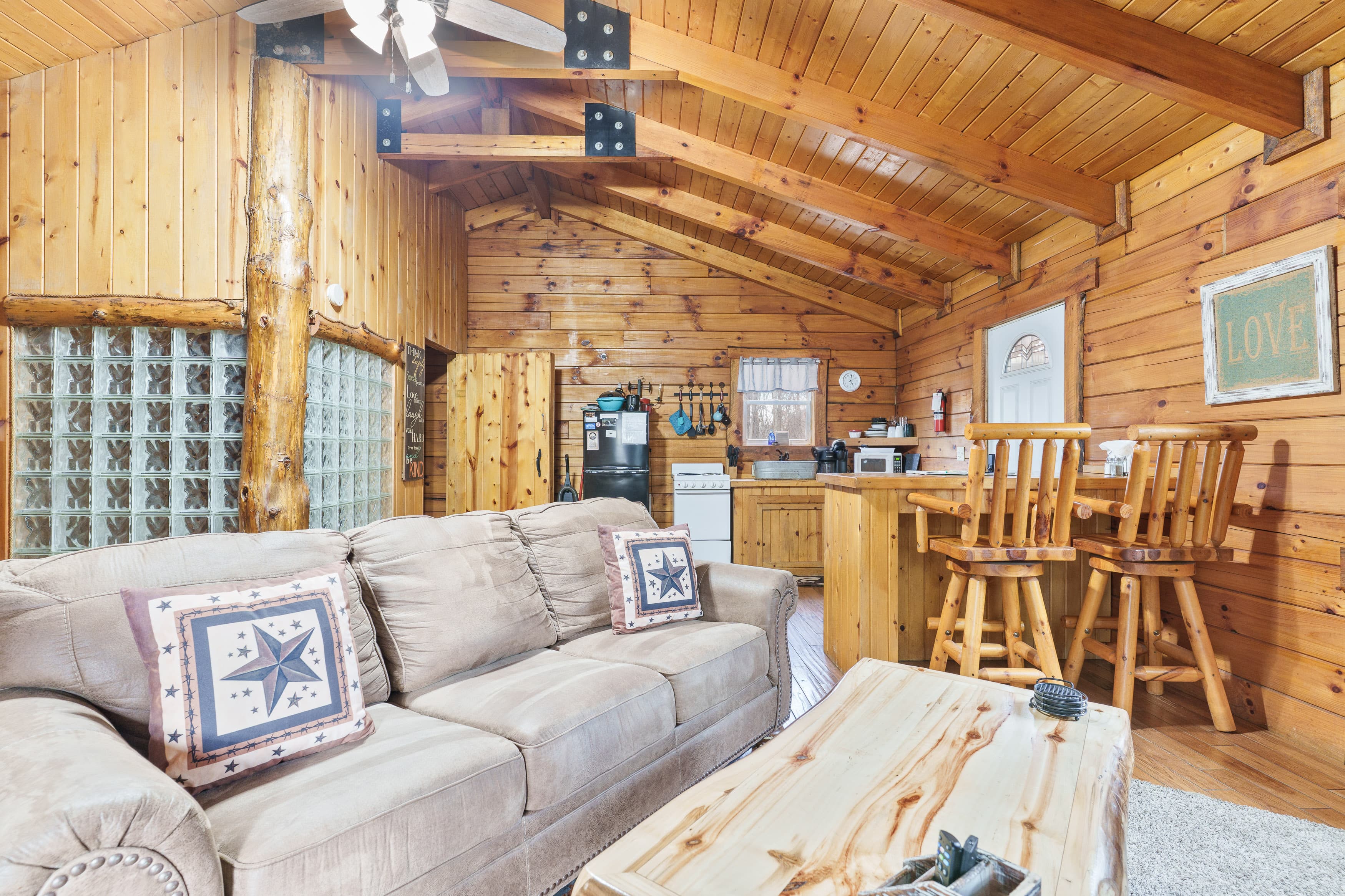 Cozy wooden interior of a cabin featuring a comfortable sofa, dining area, and kitchen.