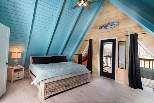 A cozy, modern loft bedroom with an angled blue ceiling and natural wood accents.