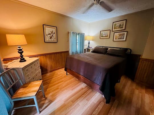 Cozy bedroom featuring a brown bedspread, wooden furniture, and warm lighting.