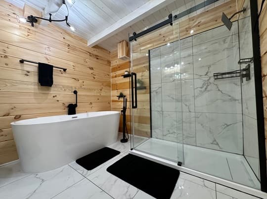 A modern bathroom featuring a freestanding tub, glass shower, and wooden accent walls.