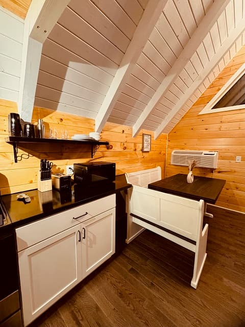 A cozy kitchen in a cabin featuring wooden accents, a microwave, and a small dining table.
