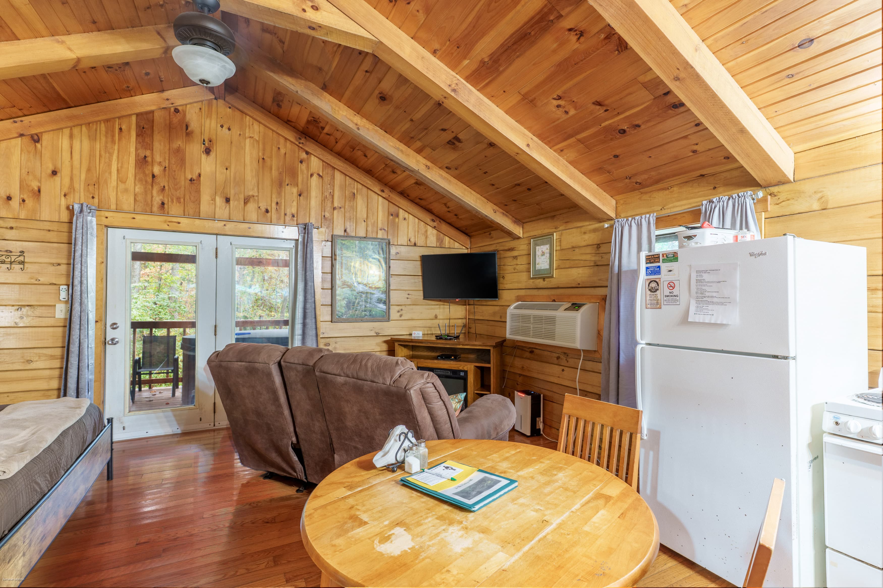 Cozy wooden cabin interior featuring a seating area, kitchenette, and dining table.