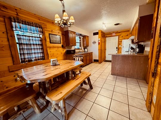 Cozy wooden kitchen featuring a rustic table, chairs, and modern appliances.