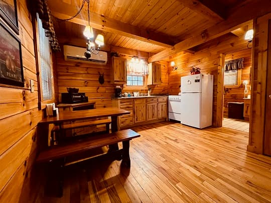 Cozy wooden kitchen featuring a dining table, appliances, and warm lighting.
