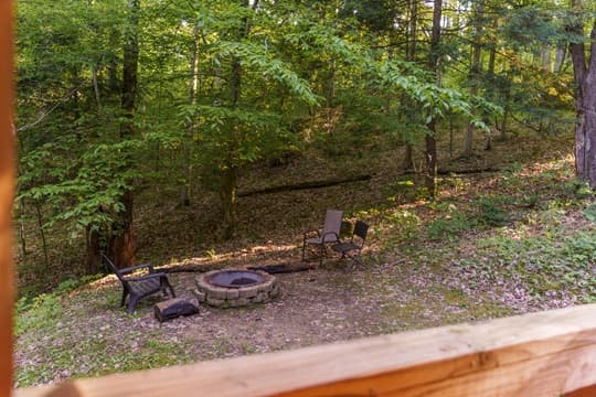 A cozy fire pit area surrounded by greenery and trees.