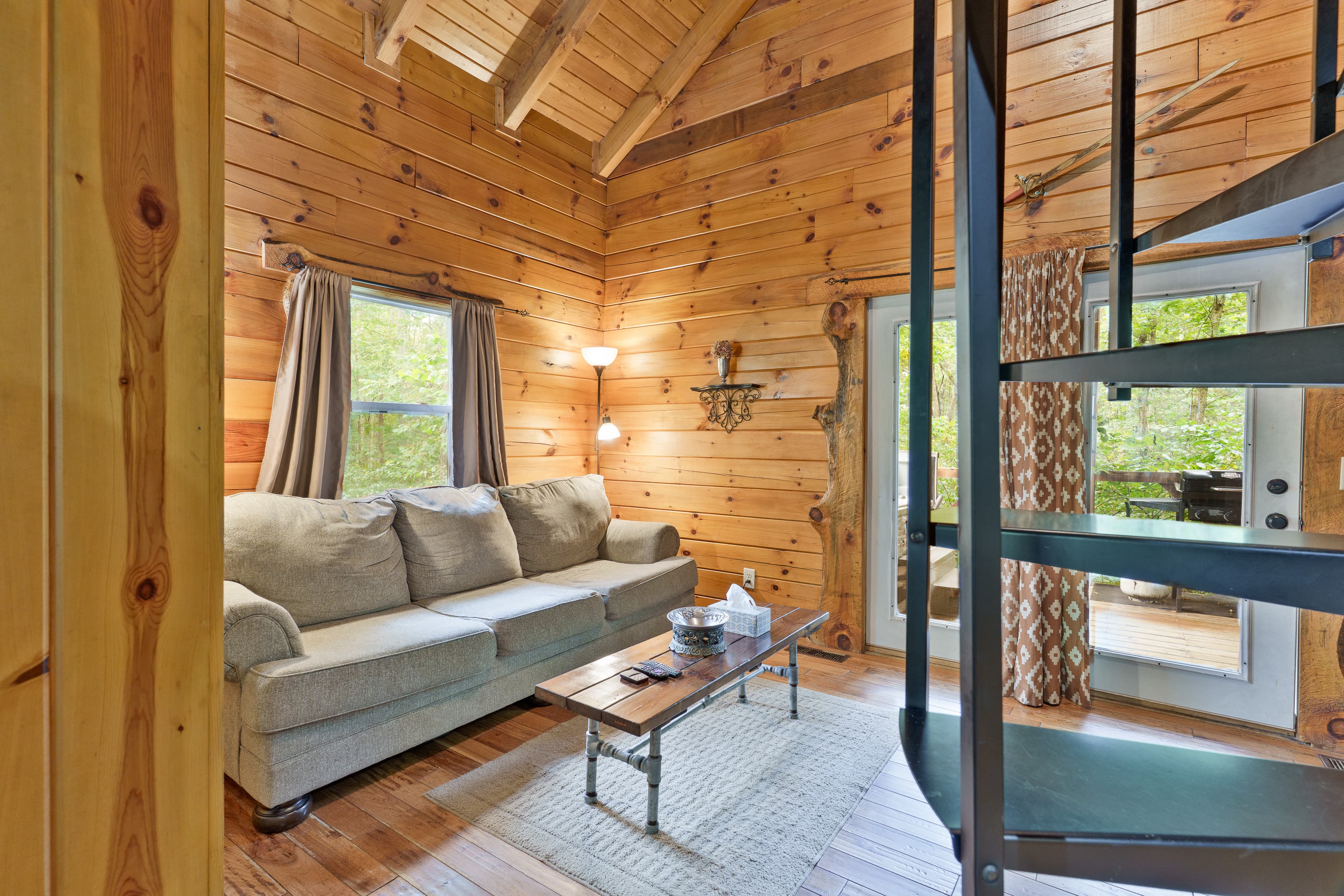Cozy living area in a wooden cabin with a sofa, coffee table, and spiral staircase.