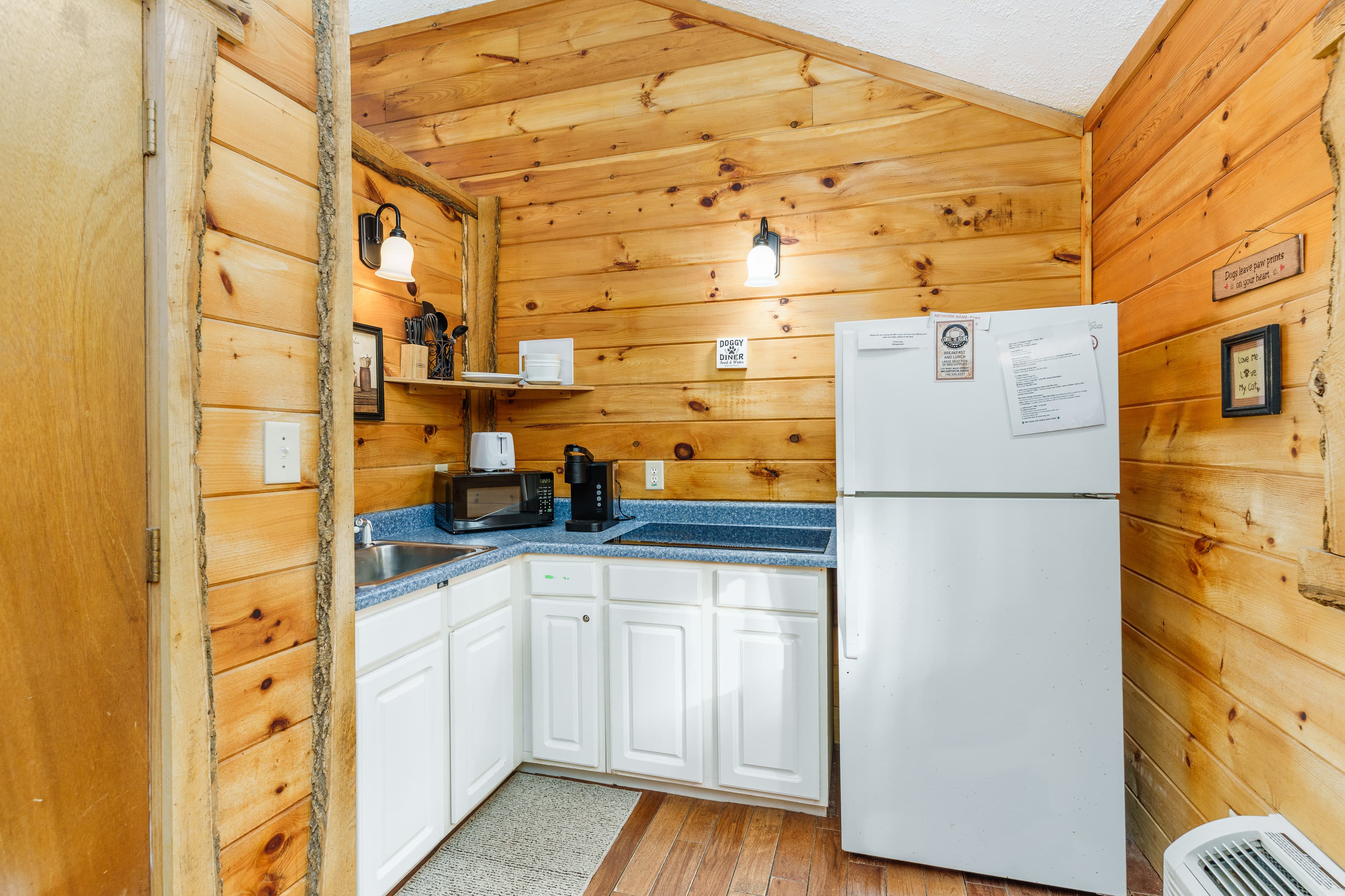 Cozy kitchen with wooden walls, featuring appliances, a sink, and a countertop.