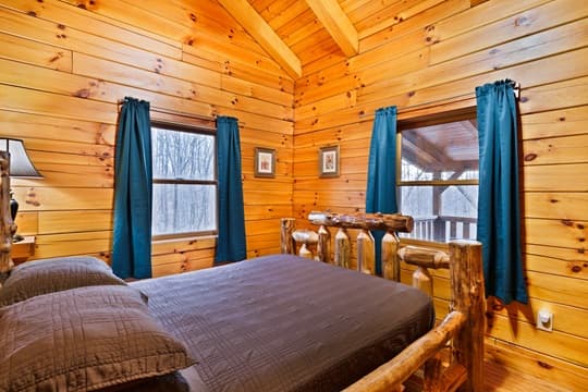 Cozy wooden cabin bedroom featuring a log bed and teal curtains.