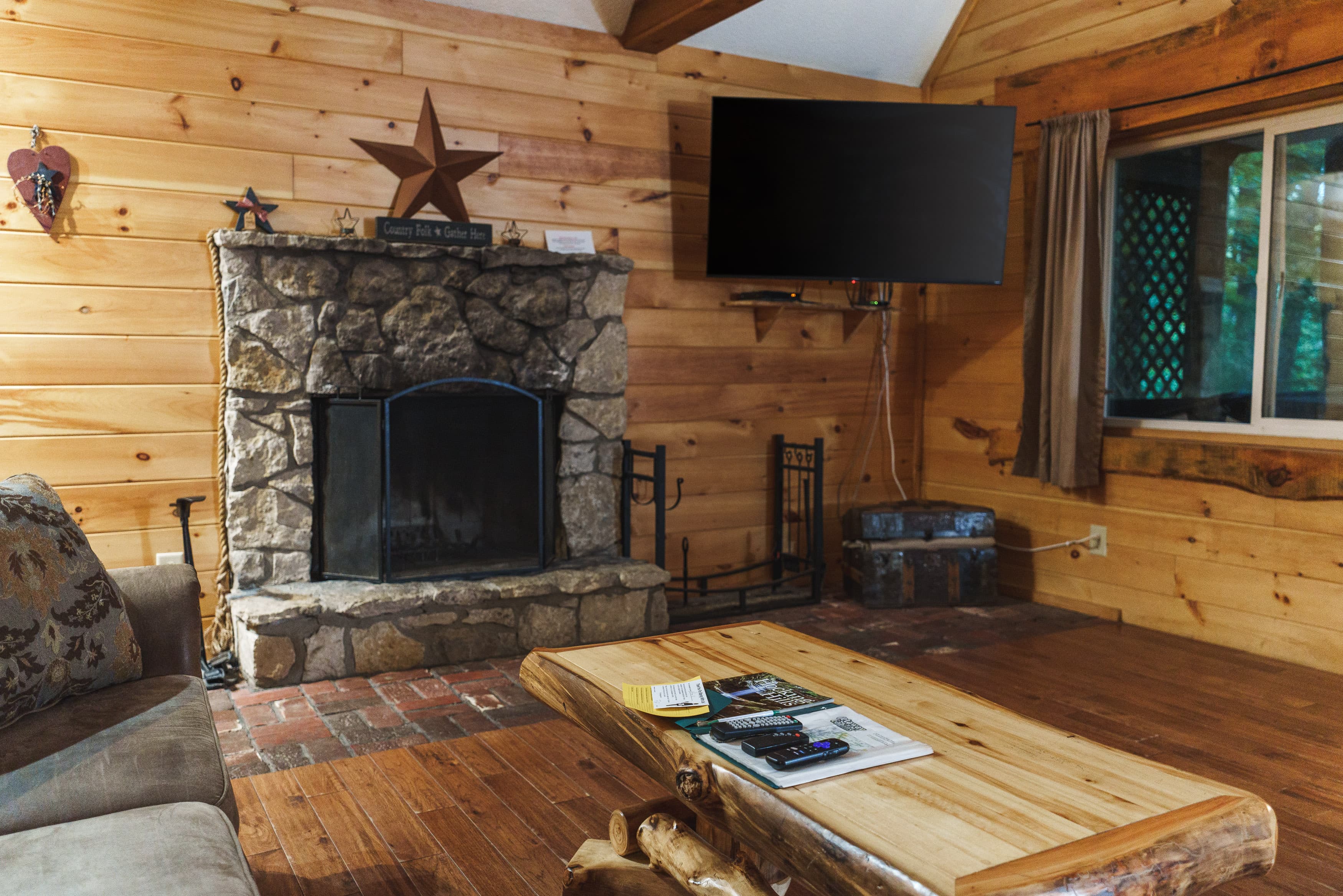 Cozy wooden living room featuring a stone fireplace, TV, and wooden coffee table.