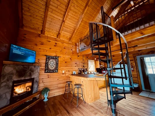 Cozy wooden cabin interior with a spiral staircase, fireplace, and a bar area.