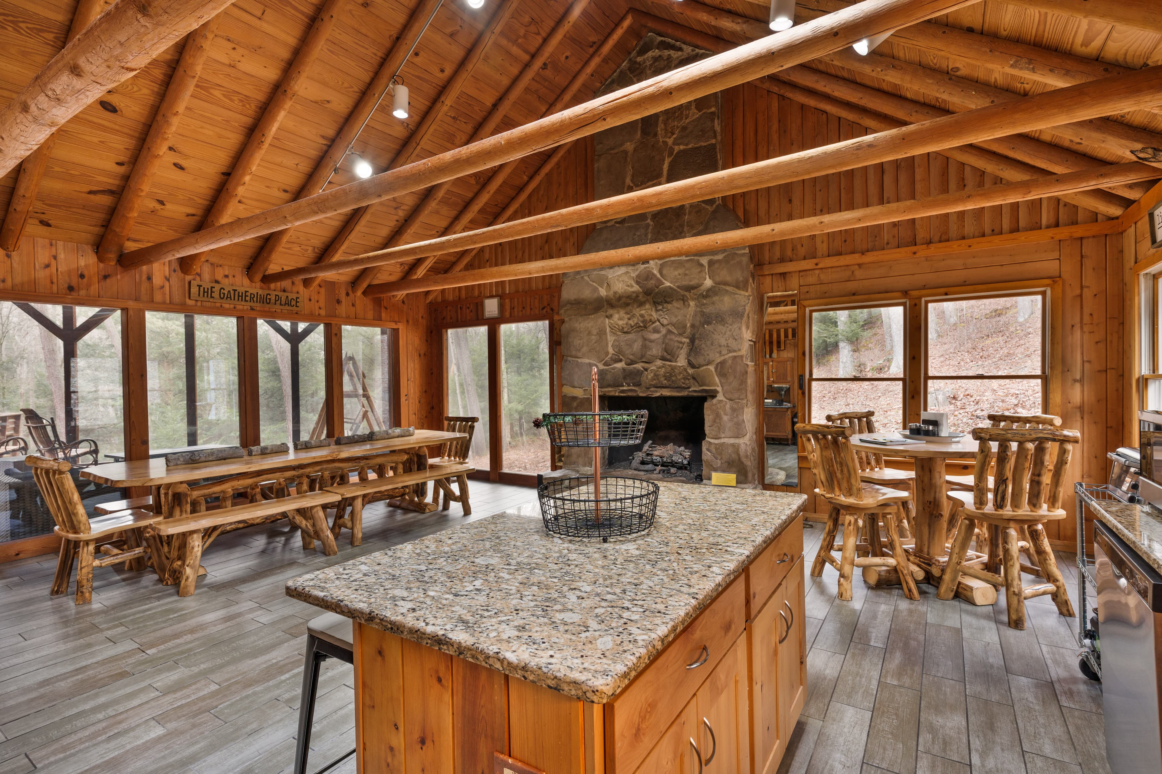 Cozy wooden kitchen and dining area featuring a stone fireplace and large windows.