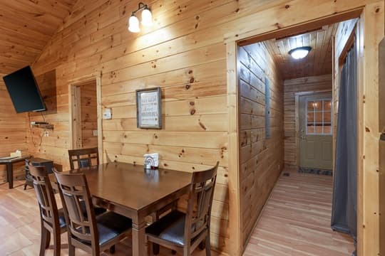 A cozy wooden dining area with a table and chairs, leading to a hallway with a door.