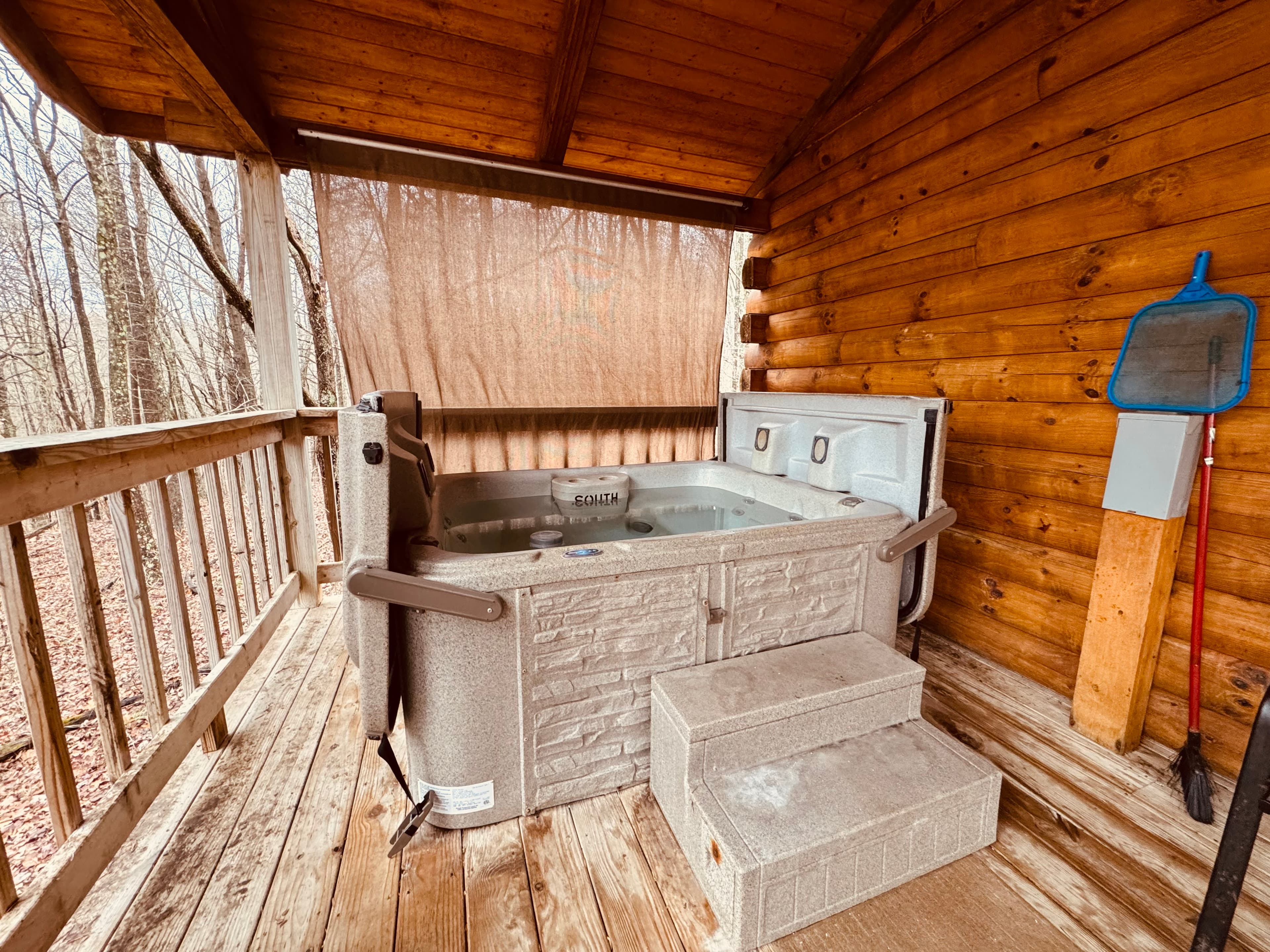 A hot tub on a wooden porch surrounded by trees.