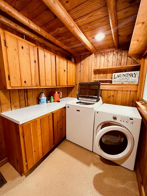 A cozy laundry room with wooden cabinets, a washer and dryer, and a decorative "LAUNDRY" sign.