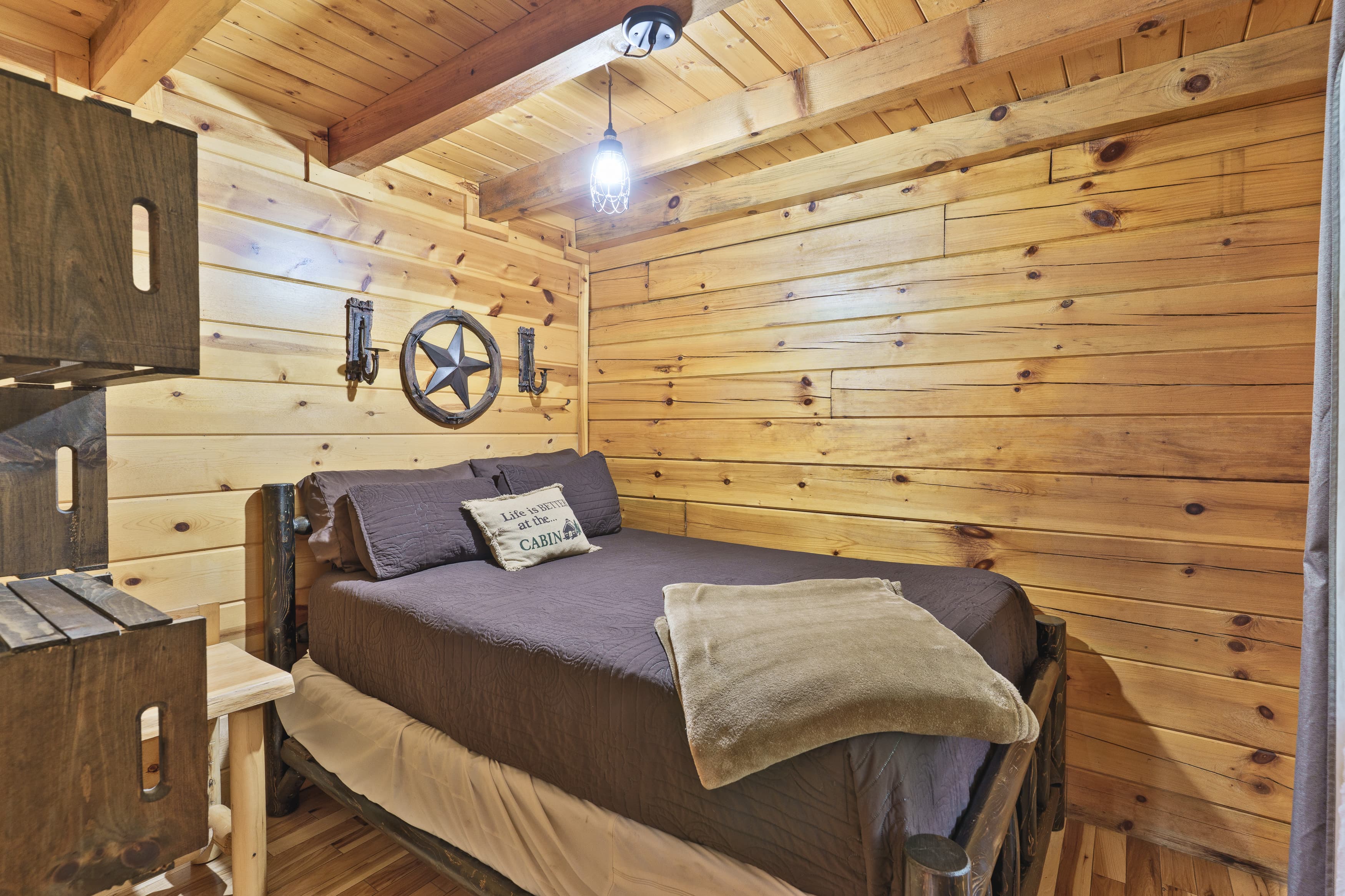 Cozy wooden bedroom featuring a bed with dark bedding and rustic decor.